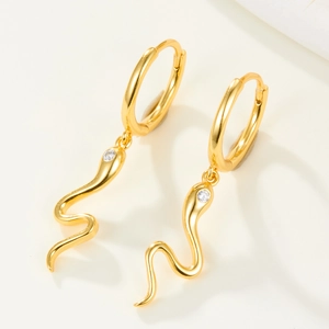 Minimalistische goldene Schlangenohrringe mit funkelndem Zirkonia auf hellem Hintergrund