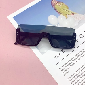 Detail view of large flat-top sunglasses with black resin frame and silver rivet accents