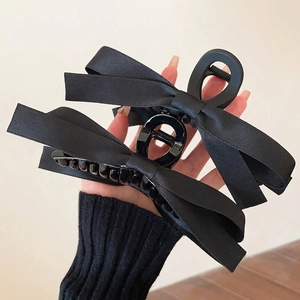 Elegant large black satin double bow hair claw clip held in hand for hair styling