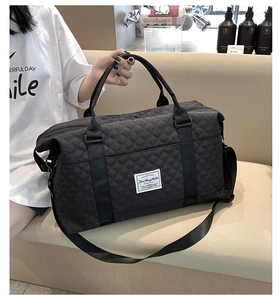 Detailed close-up of black quilted travel bag with adjustable strap and handles