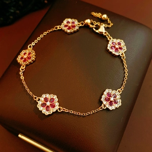 Detailed macro view of 18k gold plated flower bracelet with rubies on a leather box