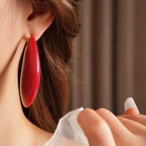 Gros plan d'une grande boucle d'oreille goutte en résine rouge portée par un mannequin