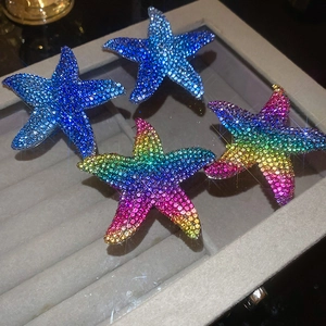Macro detail of starfish earrings with colorful pavé rhinestones in a velvet jewelry box