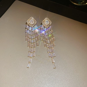 Macro detail of gold-plated geometric tassel earrings with sparkling cubic zirconia stones