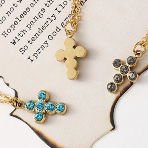 Detailed close-up of cross pendants with blue and grey crystals on vintage paper background