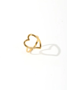 Detail of a 18k gold plated heart ring casting a heart-shaped shadow on white surface