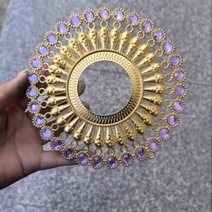 Close-up of golden circular metal wall decor with purple gemstone inlay detail