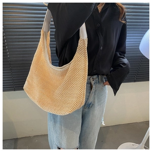 Detail of beige woven shoulder bag with light grey strap on a casual model outfit