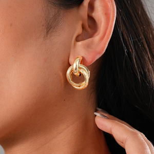 Macro shot of elegant triple-interlocking gold-tone hoop earrings worn by a female model