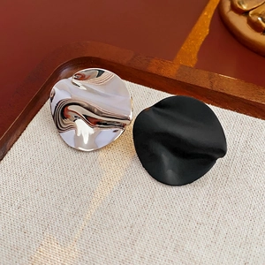 Detail of asymmetric crumpled metal stud earrings in silver and matte black finish