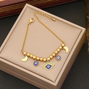 Detailed macro view of golden beads bracelet with blue evil eye and moon enamel charms