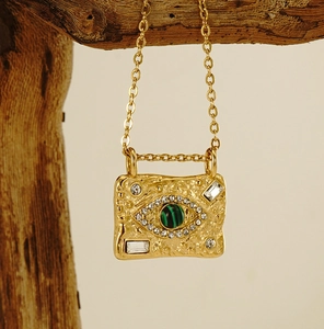 Macro detail of 18K gold evil eye necklace with malachite stone and textured hammer finish