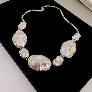 Detailed view of silver irregular crinkled metal plates on a modern necklace chain