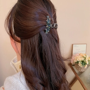 Détail de la pince à cheveux florale en métal avec strass bleus et verts portés