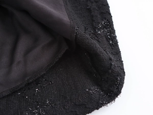 Close-up detail of elegant black evening dress fabric with shimmering metallic threads
