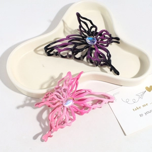 Detailed shot of gradient pink and purple butterfly hair claws on a beige tray