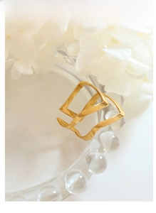 Close-up of geometric hollow rose gold open ring on textured glass with flowers