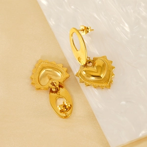 Boucles d'oreilles cœur en acier titane doré avec bords texturés sur fond beige chaud