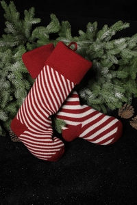 Close-up of red and white striped knit Christmas stockings with pine branches and cones