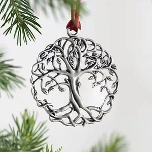 Silver tree of life metal ornament with red ribbon hanging on a blurred Christmas tree