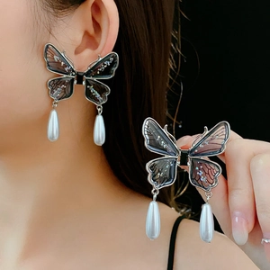 Detailed close-up of butterfly earrings with shimmering wings and waterdrop pearl pendants