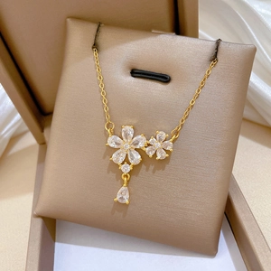 Detail of gold flower necklace with sparkling zircon petals and a teardrop pendant