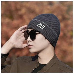 Detailed close-up of dark grey ribbed knit beanie with stylish brand label outdoors