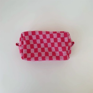 Detail of pink checkerboard knit cosmetic bag with zipper and side handle strap
