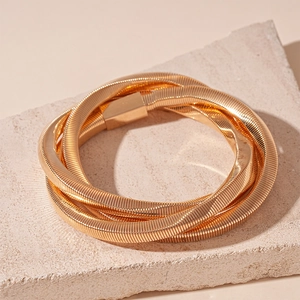 Detailed macro view of gold multi-layered snake bone texture bracelet on stone base