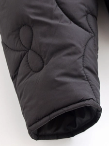 Close-up of black wave-quilted jacket cuff showing detailed stitching and fabric texture