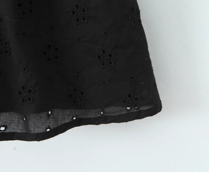 Vue détaillée de l'ourlet de robe noire avec broderie florale ajourée délicate