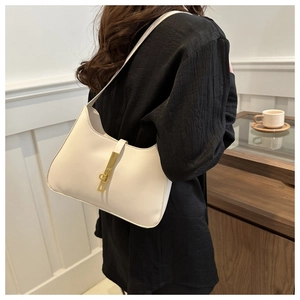 Detail of a beige crescent underarm bag featuring a classic gold piston metal clasp