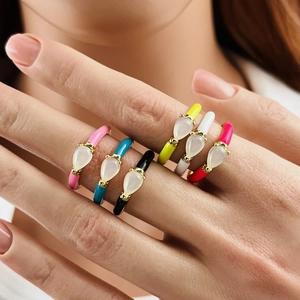 Close-up of six colorful enamel rings with water drop shaped stones on a model's hand
