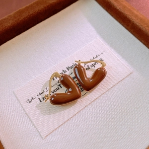 Detail of vintage heart earrings with brown enamel finish on textured linen card