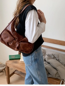 Brown vintage baguette bag with adjustable strap shown on shoulder in a retro setting
