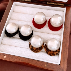 Close-up of pearl stud earrings with black, red and leopard print velvet charms in box