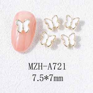 Détail macro de breloques papillon en émail blanc bordé d'or 7,5x7 mm pour nail art chic