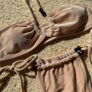 Detail of velvet bikini top with glossy texture and decorative blue amber beads