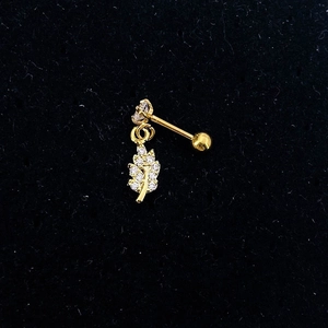 Close-up of golden leaf pendant stud earring with clear zircon inlay on black velvet