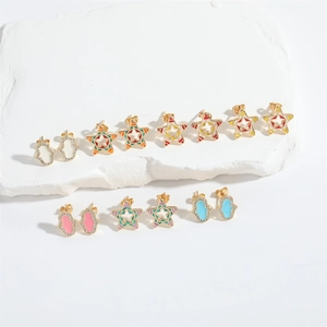 Detail view of gold star and Hamsa Hand earring set with colorful enamel on stone stand