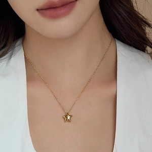 Collier minimaliste avec pendentif étoile 3D dorée porté par un mannequin féminin