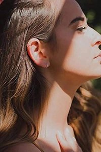 Close-up of minimalist gold titanium steel hoop earrings worn on earlobe and helix cartilage