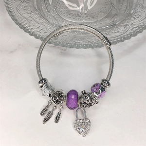 Dettaglio di un bracciale argento con perle viola e pendente a forma di piuma