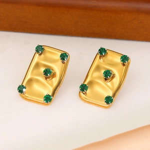 Macro shot of gold rectangle earrings featuring wave texture and green gemstones