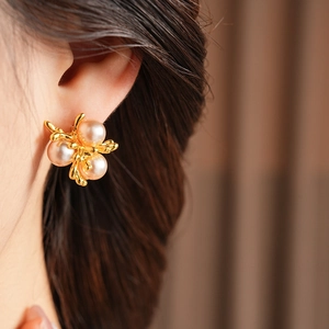 Close-up of elegant gold branch-shaped earrings with pearls on model's ear