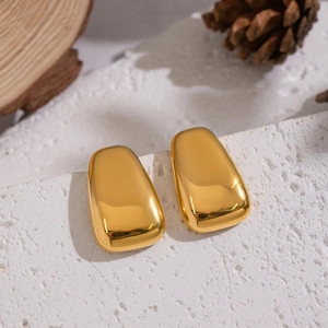 Minimalist geometric gold earrings with polished mirror finish on rustic stone base