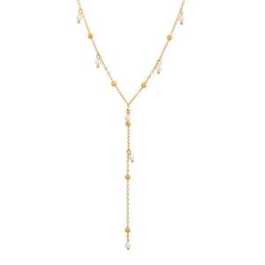 Dettaglio della collana a Y dorata con piccole perle bianche e sfere d'oro su sfondo bianco