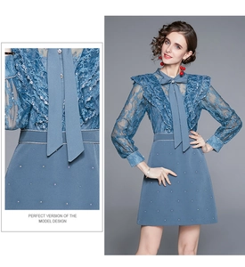 Détail d'une robe bleue en dentelle avec broderies et ruban élégant au col montant