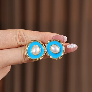 Detail of vintage gold earrings with sky blue enamel and center oval white pearl