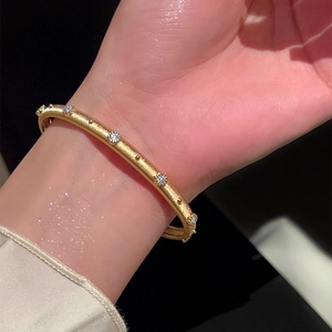 Detailed view of gold-plated brushed metal bangle with round white zircon stones on wrist